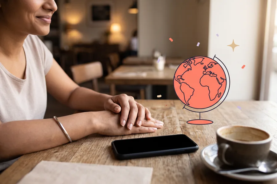 Hands resting on a cafe table beside a phone and a coffee
