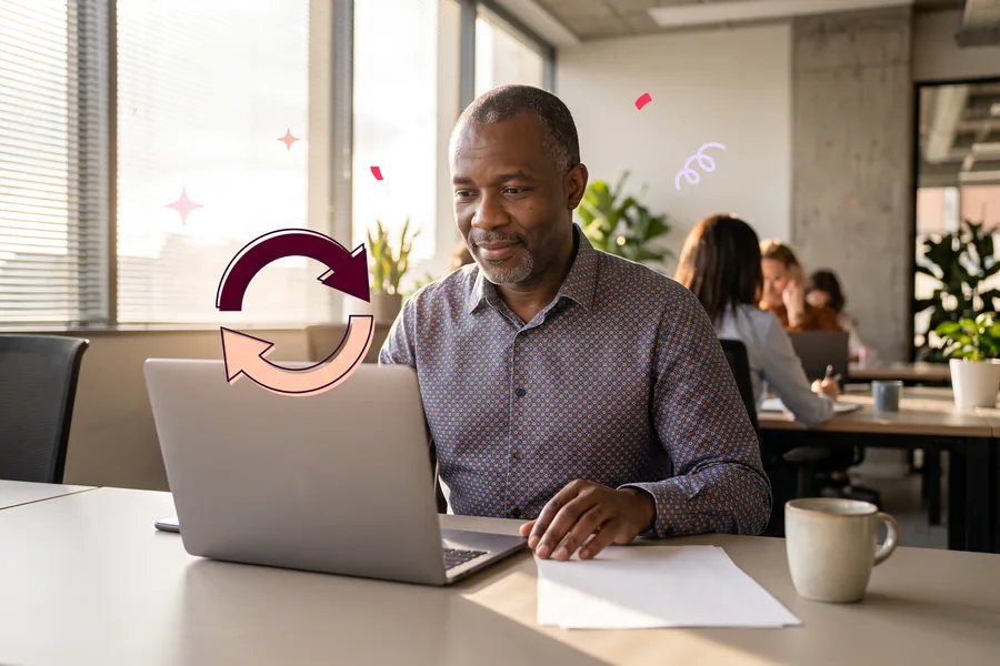 Man at a shared office desk reviewing refunds on a laptop