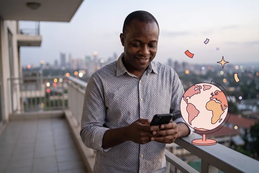 Man checking his phone on an apartment balcony at dusk