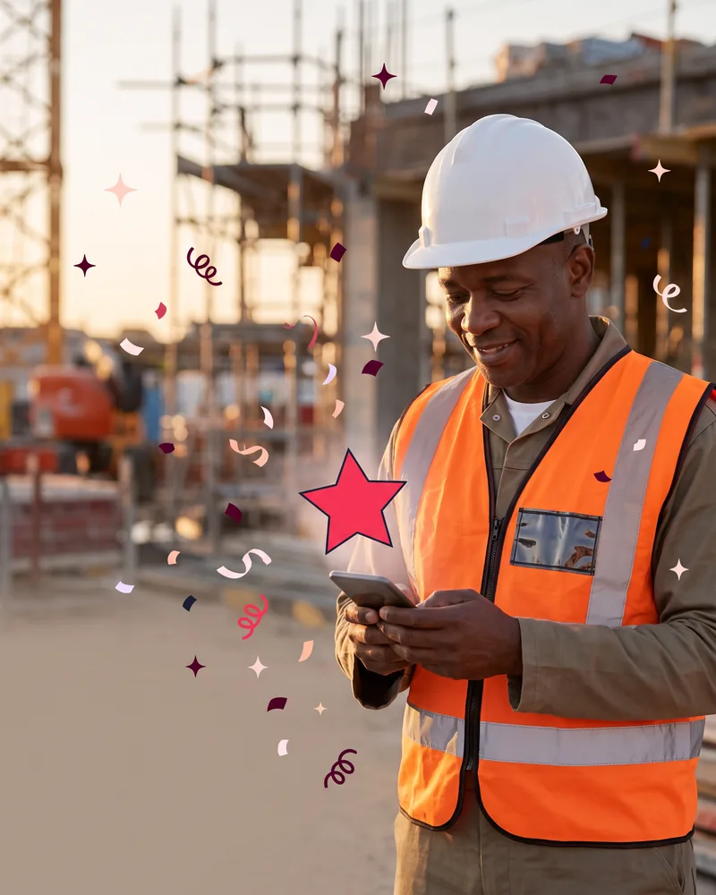 Construction foreman in a hard hat and hi-vis vest reading his phone on site