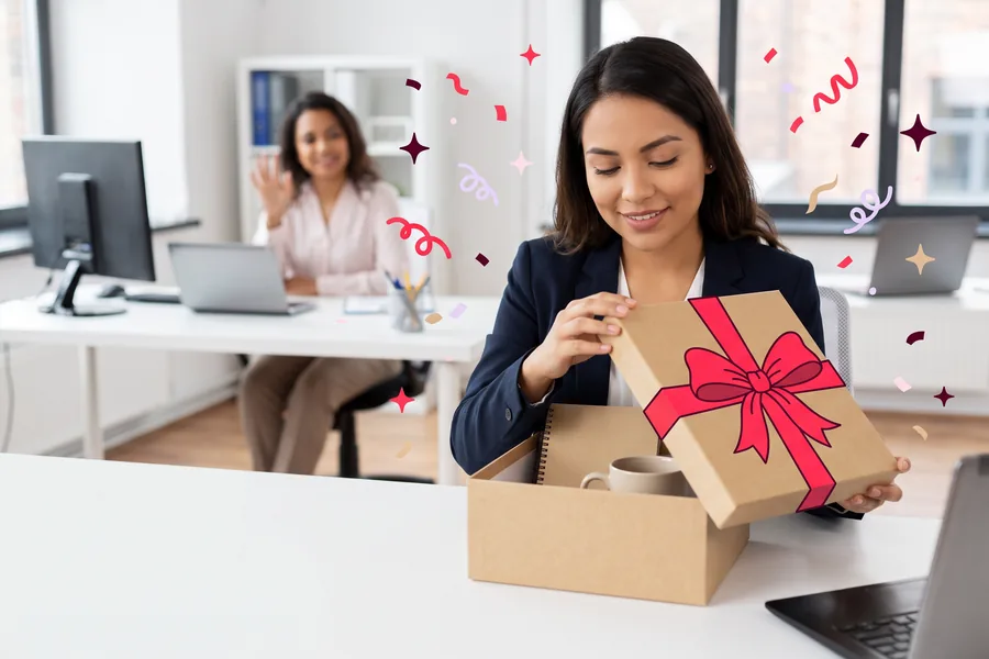 New hire opening a welcome box with a notebook and mug at her desk on her first morning