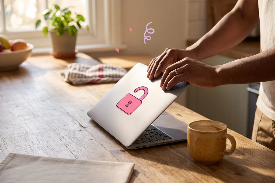 Hands closing a laptop on a kitchen table beside a coffee