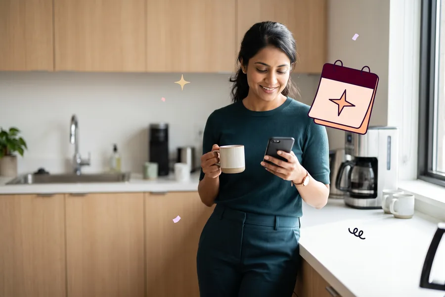 Woman at an office kitchen counter with a coffee, smiling at her phone