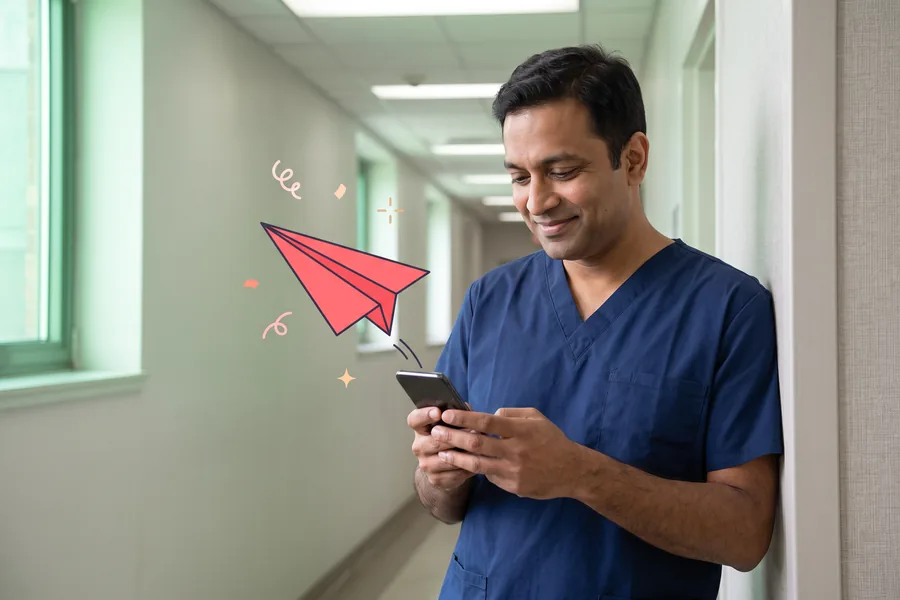 Charge nurse leaning on a corridor wall between rounds, using his phone