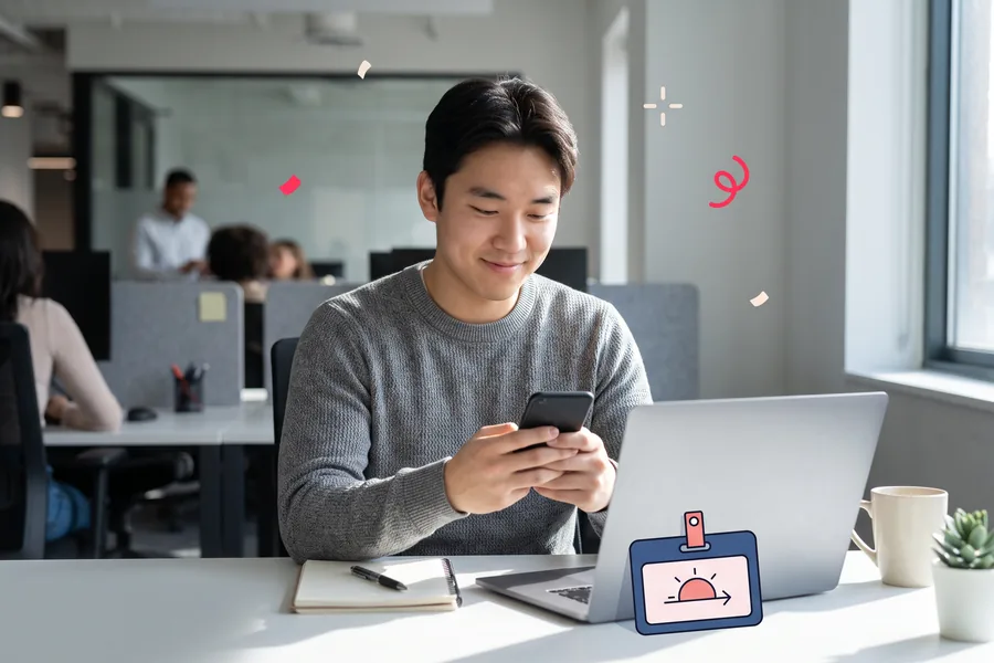 New intern at a shared desk on his first morning, reading his phone beside a name badge