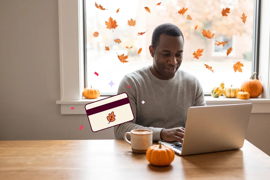 Founder at a coffee shop laptop with a small pumpkin on the table, autumn leaves outside