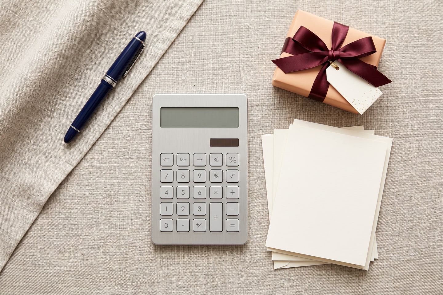 A calm desk with a calculator, greeting cards and a small wrapped gift arranged for budget planning