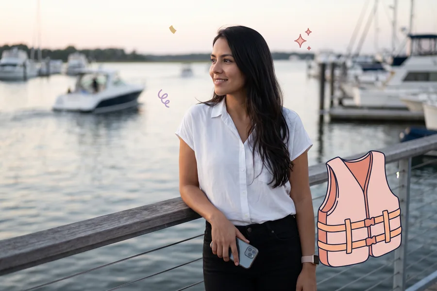 Woman at a marina rail at dusk looking out at the water, a life vest beside her