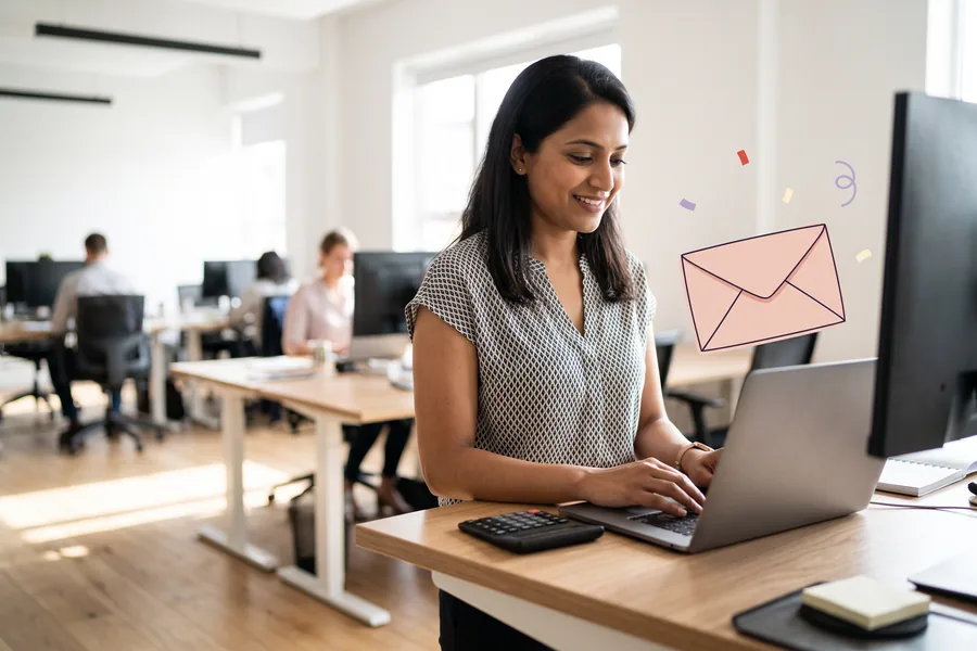 Woman at a standing desk pausing over her keyboard with a smile